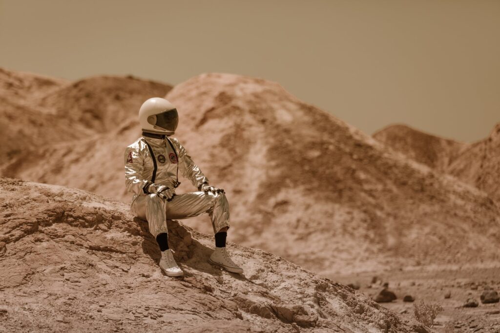 a man in space suit sitting on a rock